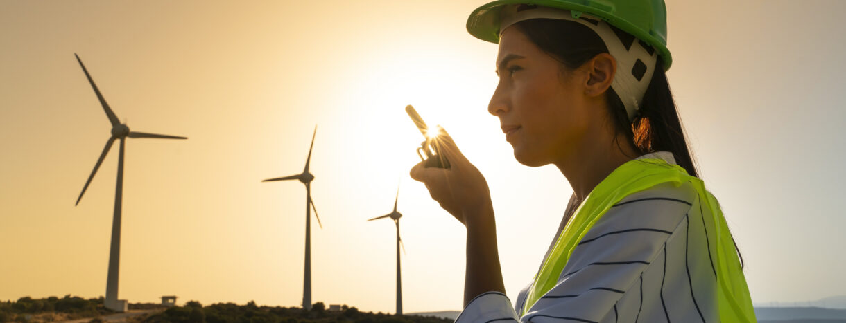 Junger Wartungstechnikerin bei der Arbeit in einer Windkraftanlage bei Sonnenuntergang.