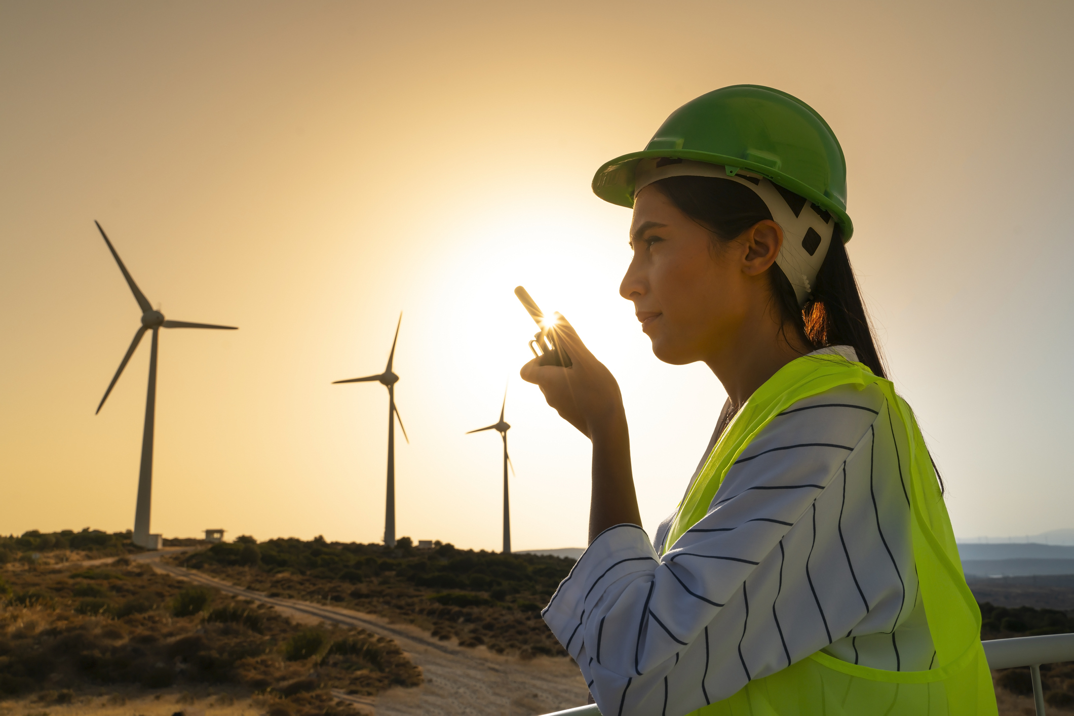Junger Wartungstechnikerin bei der Arbeit in einer Windkraftanlage bei Sonnenuntergang.